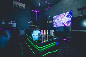 Zona de bar con luces de neón, una pantalla de televisión y una barra.
