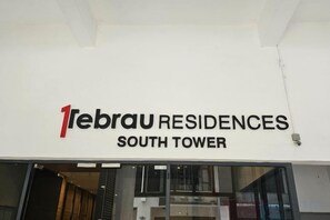 La façade extérieure de la tour sud du complexe 1ebrau Residences, avec une enseigne bien visible.