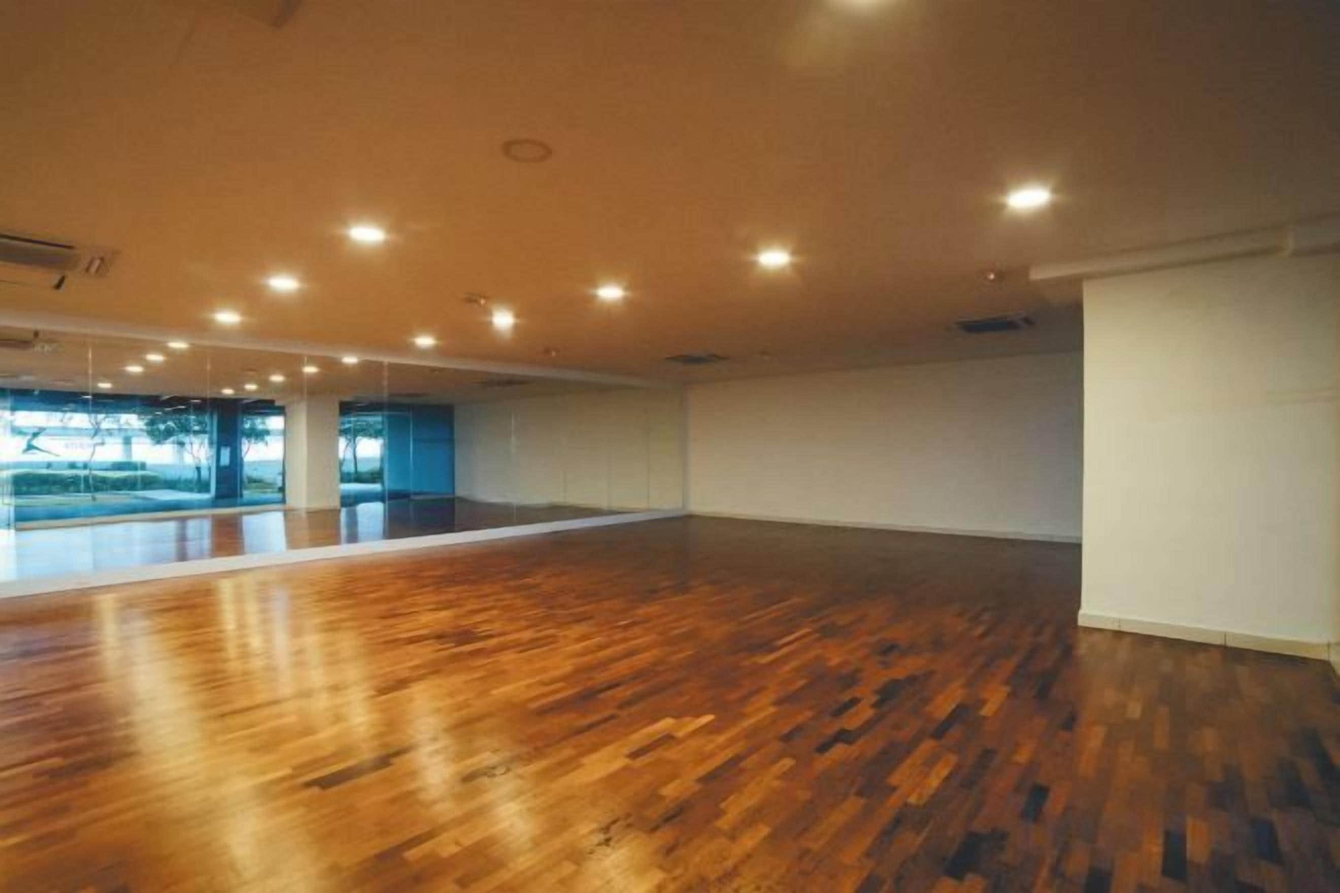 A spacious room with a wooden floor and a large window.