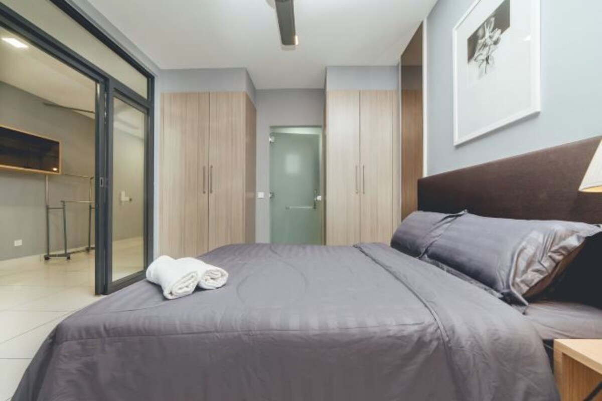 Una habitación de hotel moderna con una cama grande, un televisor de pantalla plana y una puerta corredera de vidrio que da a un baño.