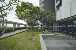 Une cour avec une pelouse, des arbres et un bâtiment doté de grandes fenêtres.