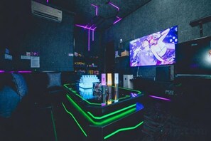 Zona de bar con iluminación de neón, una pantalla de televisión y una barra.
