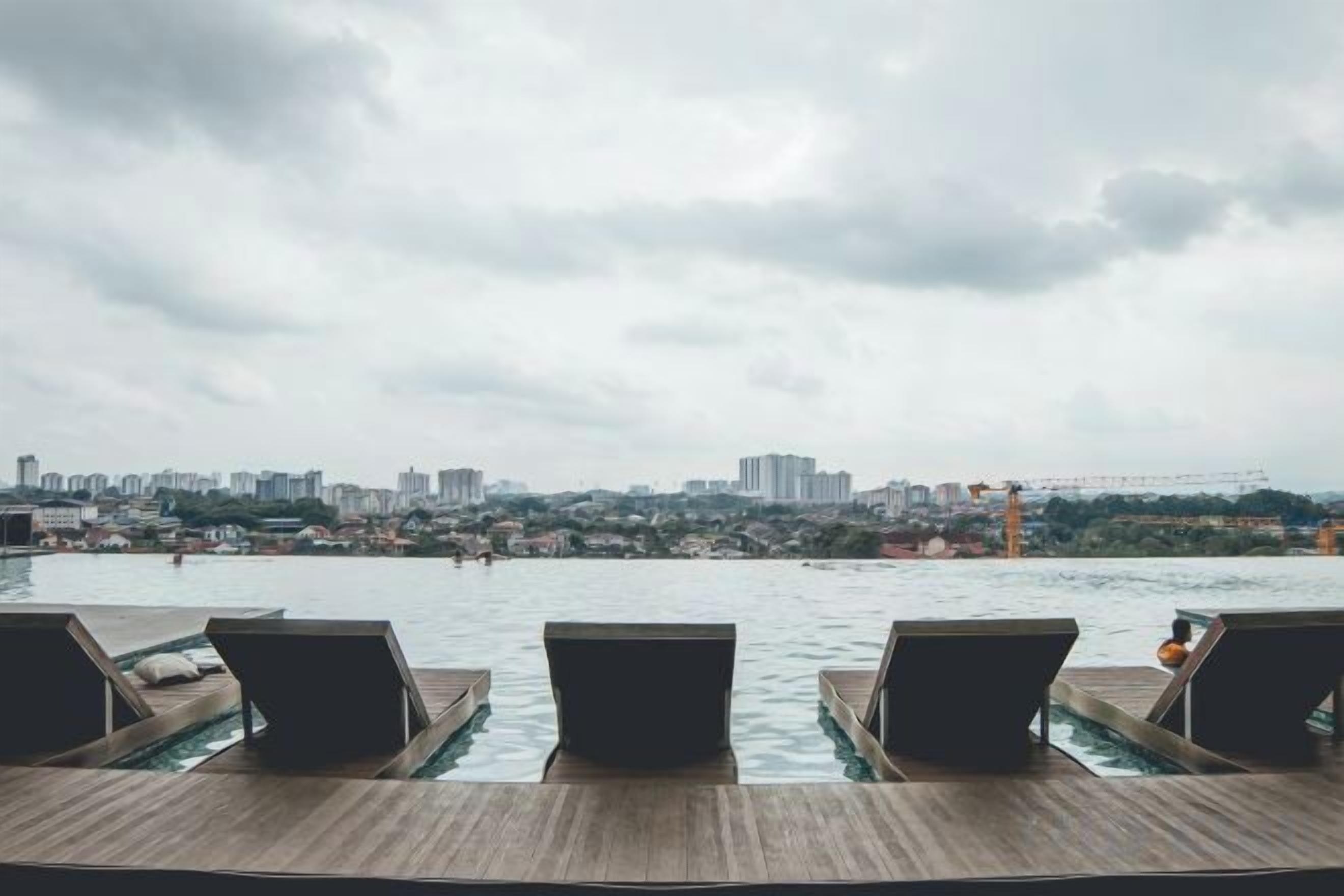 Une vue sur le front de mer, avec des chaises longues et un paysage urbain en arrière-plan.