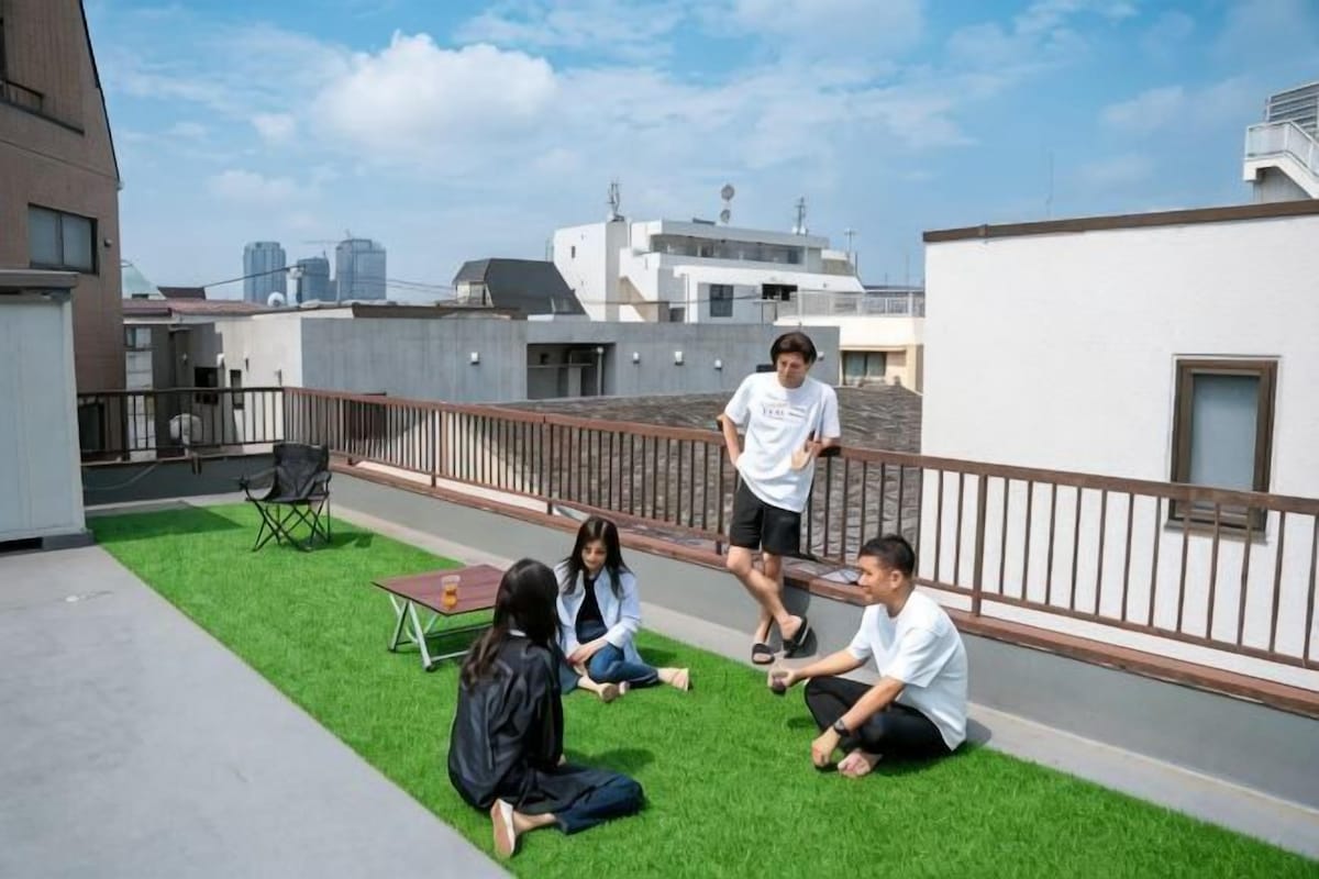 Una terraza en la azotea con césped, una mesa y una barandilla.