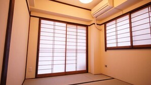 Una stanza tradizionale giapponese con pavimento in tatami, porte scorrevoli shoji e una ventola a soffitto.