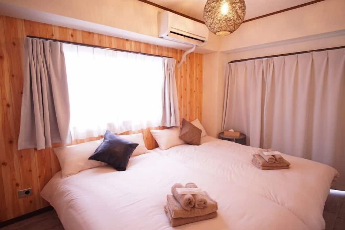 A bedroom with a large bed, wooden walls, and a hanging light fixture.
