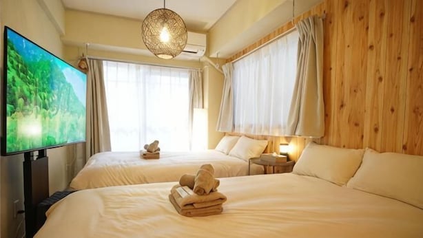 Una camera d'albergo con due letti, una televisione, una lampada e un muro in legno.
