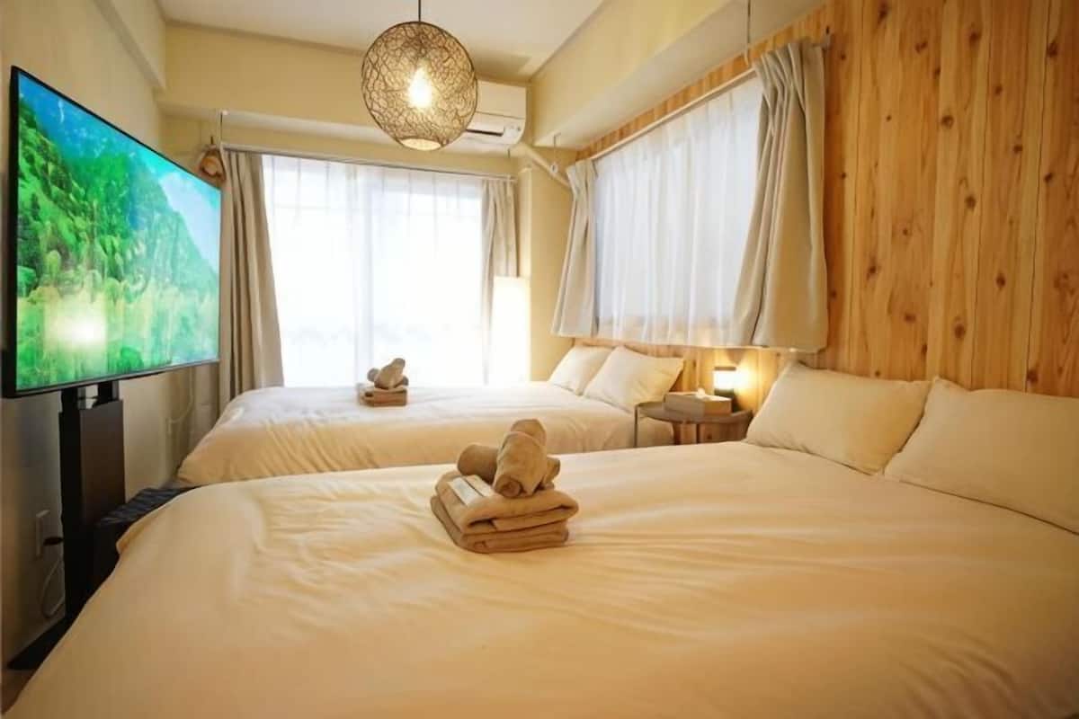 A hotel room with two beds, a television, a lamp, and a wooden wall.