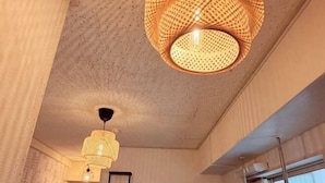 Una stanza con soffitto strutturato, una grande finestra con persiane e una scala in metallo.
