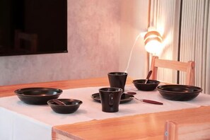 A dining table with several bowls and cups, a chair, and a wall-mounted light fixture.