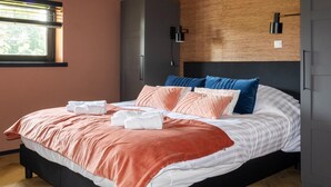 A neatly made bed with a pink and white duvet, blue pillows, and a wooden headboard. - Charming Holiday Home in Kiel-Windeweer (Kiel-Windeweer)