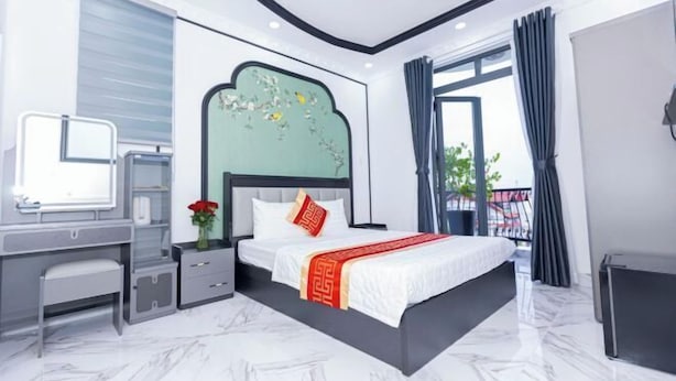 A modern hotel room with a large bed, a desk, and a view of the outdoors. - Phu Gia Hotel 2160 Huynh Tan Phat (Ho Chi Minh City)