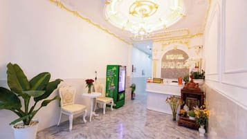 Un hall de hotel con mostrador de recepción, zona de estar y un techo decorativo.