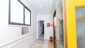 A hallway with a large window, a fire extinguisher, and a door with a yellow frame. - Phu Gia Hotel 2160 Huynh Tan Phat (Ho Chi Minh City)