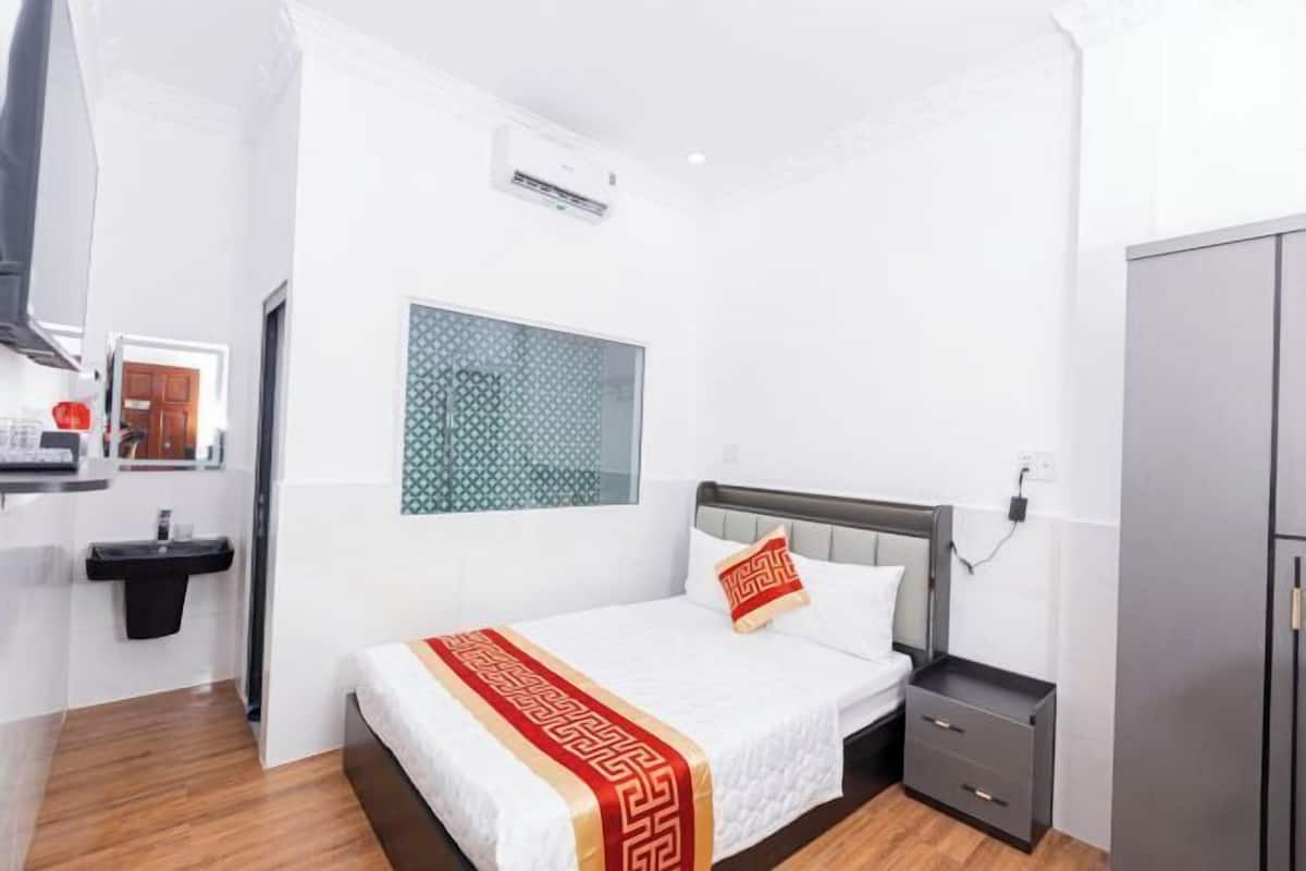 Quarto de hotel moderno com cama, mesa de cabeceira e guarda-roupa.