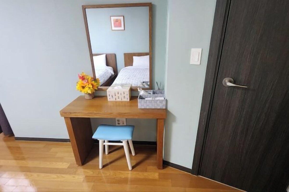 A room with a wooden desk, a blue bench, a mirror, and a door.