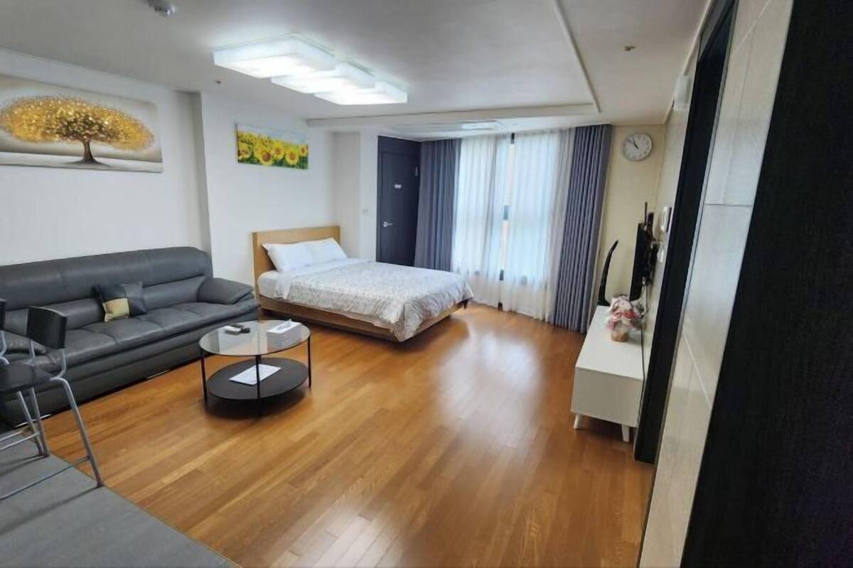 A modern hotel room with a bed, a sofa, a small table, and a nightstand.