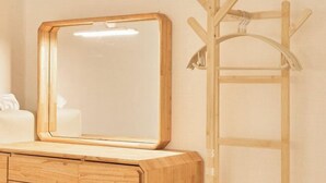 Una cassettiera in legno con uno specchio e un attaccapanni.