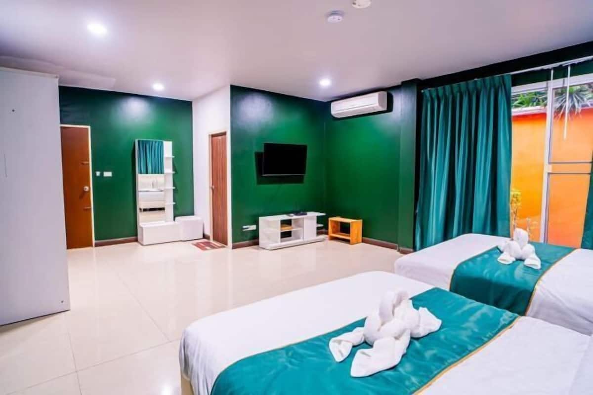 Une chambre d’hôtel avec deux lits, un téléviseur, un petit meuble pour le téléviseur, un miroir et un appareil de climatisation.