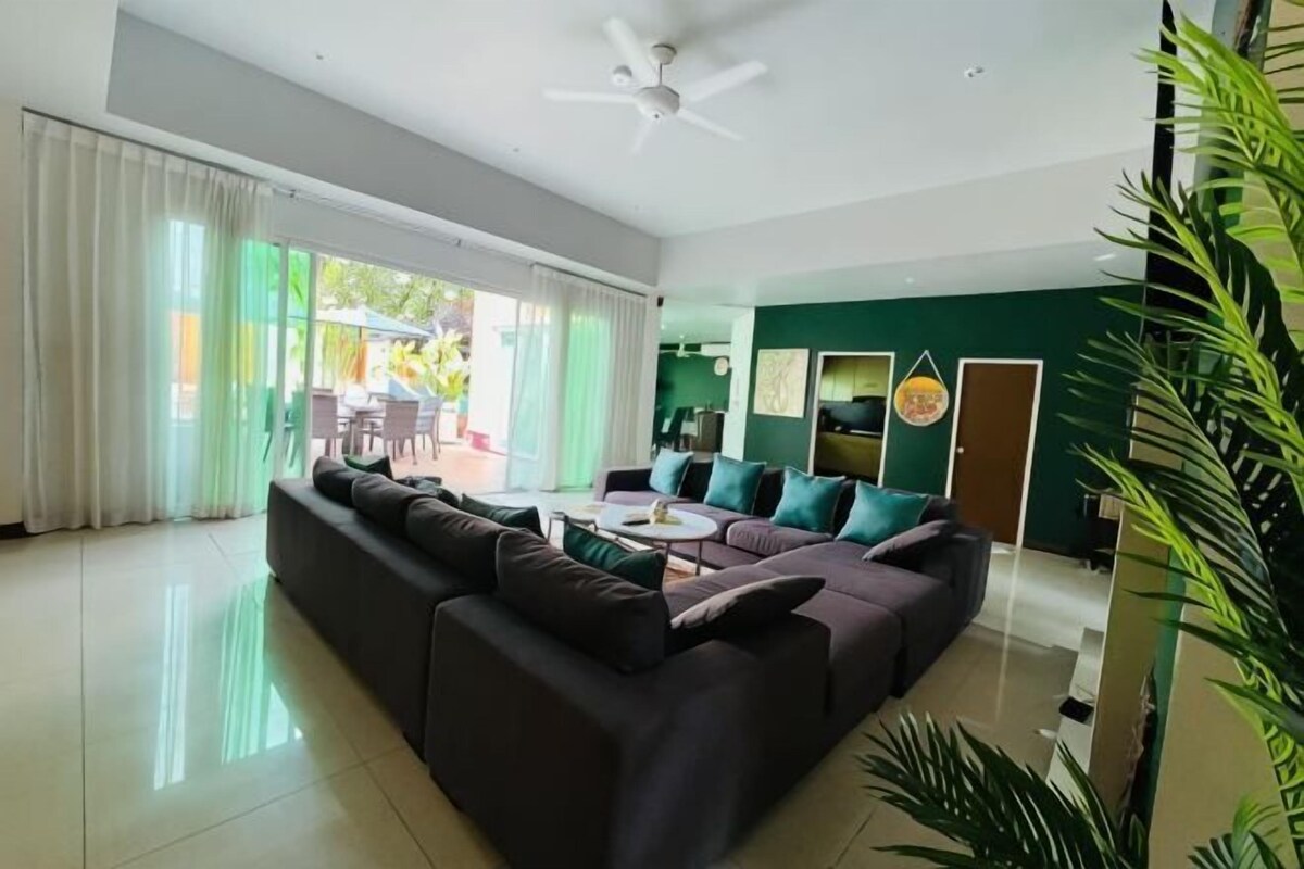 A modern living room with a sectional sofa, a ceiling fan, and a view of the outdoors.