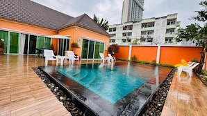 A swimming pool with a tiled deck, surrounded by lounge chairs and a building with a tiled roof. - The Ace 6 Bedrooms 6 Bathrooms Villa With Free Bills (Pattaya)