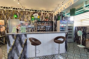 Un espace bar avec un comptoir, deux tabourets et un assortiment de bouteilles.