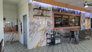 Um saguão de hotel com um balcão de recepção, uma parede de mármore e um piso estampado.