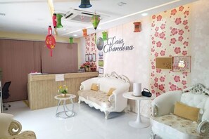 A reception area with a counter, two sofas, a small table, and decorative elements like a wall clock and framed pictures. - Townhouse Oak Casa Barcelona (Iloilo City)