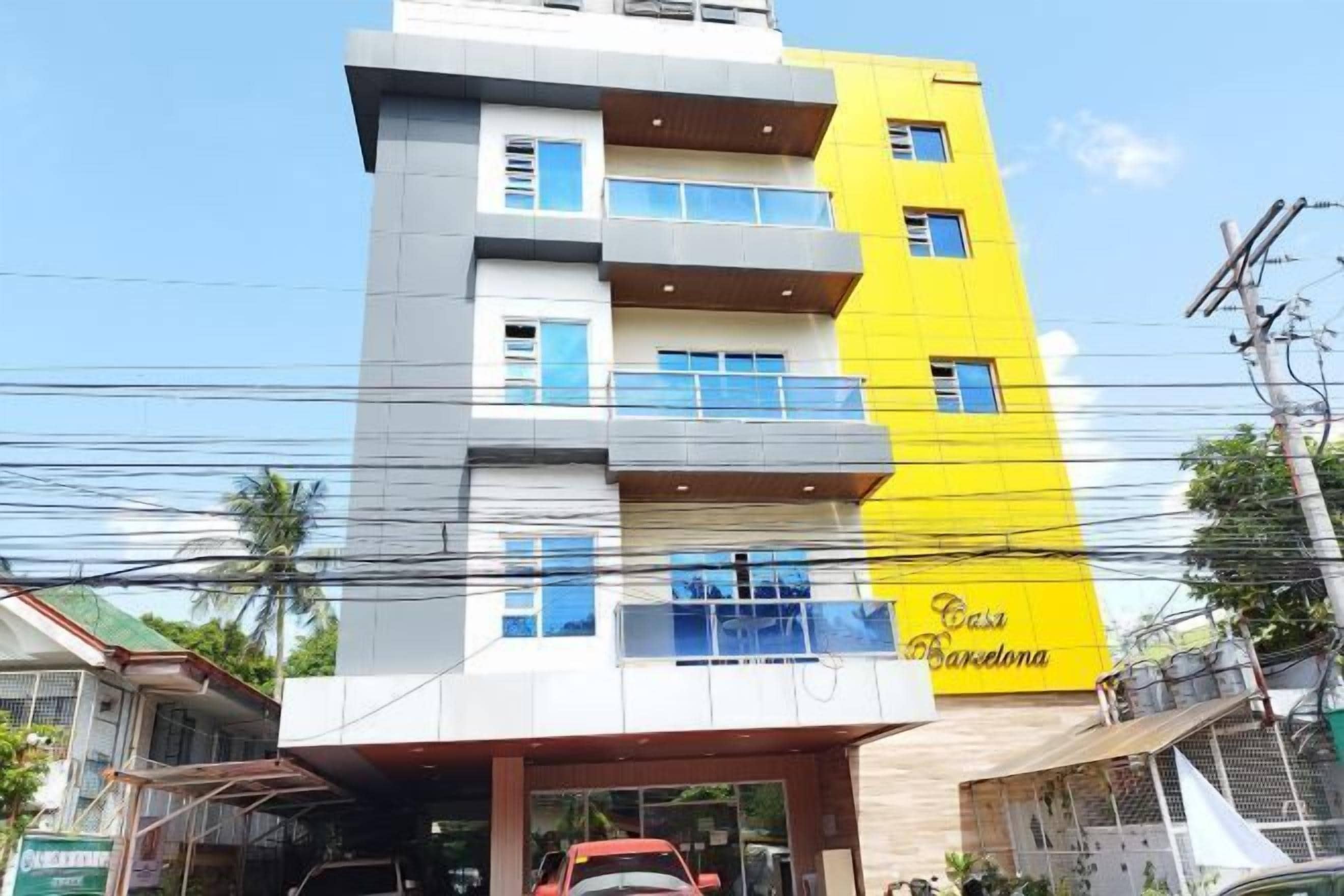 A multi-story building with balconies, a visible entrance, and a sign that reads 'Casa Barcelona.'