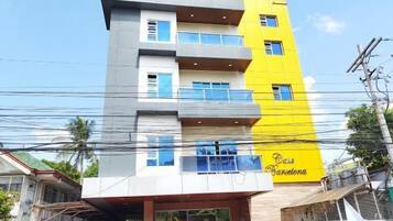 A multi-story building with balconies, a visible entrance, and a sign that reads 'Casa Barcelona.'