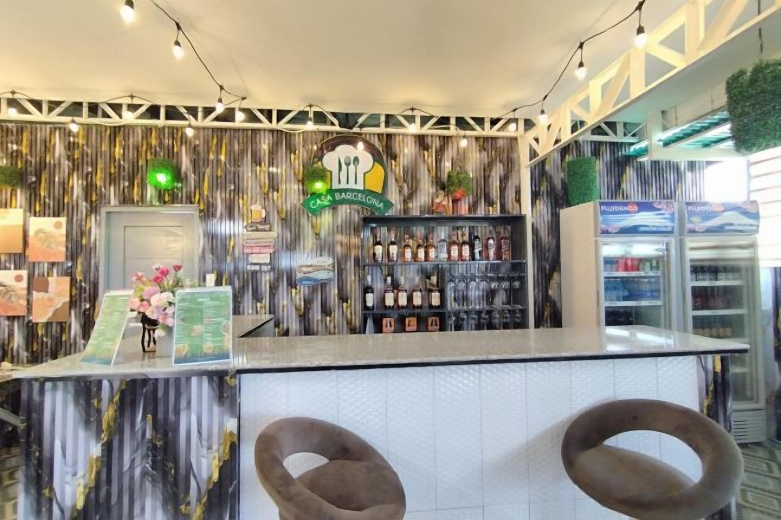 A bar area with a counter, two chairs, and a shelf with bottles.