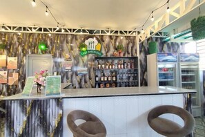 A bar area with a counter, two chairs, and a shelf with bottles. - Townhouse Oak Casa Barcelona (Iloilo City)