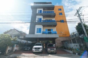 A multi-story building with a flat roof, a covered parking area, and a sign indicating 'San Fernando.'