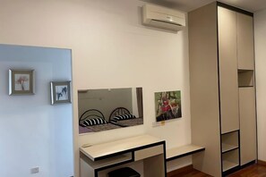 Une chambre avec un lit, un bureau, un miroir et une armoire.