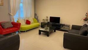 Ein modernes Wohnzimmer mit einem roten Sofa, einem gelben Sofa und einem schwarzen Sofa. In der Mitte steht ein Glastisch.