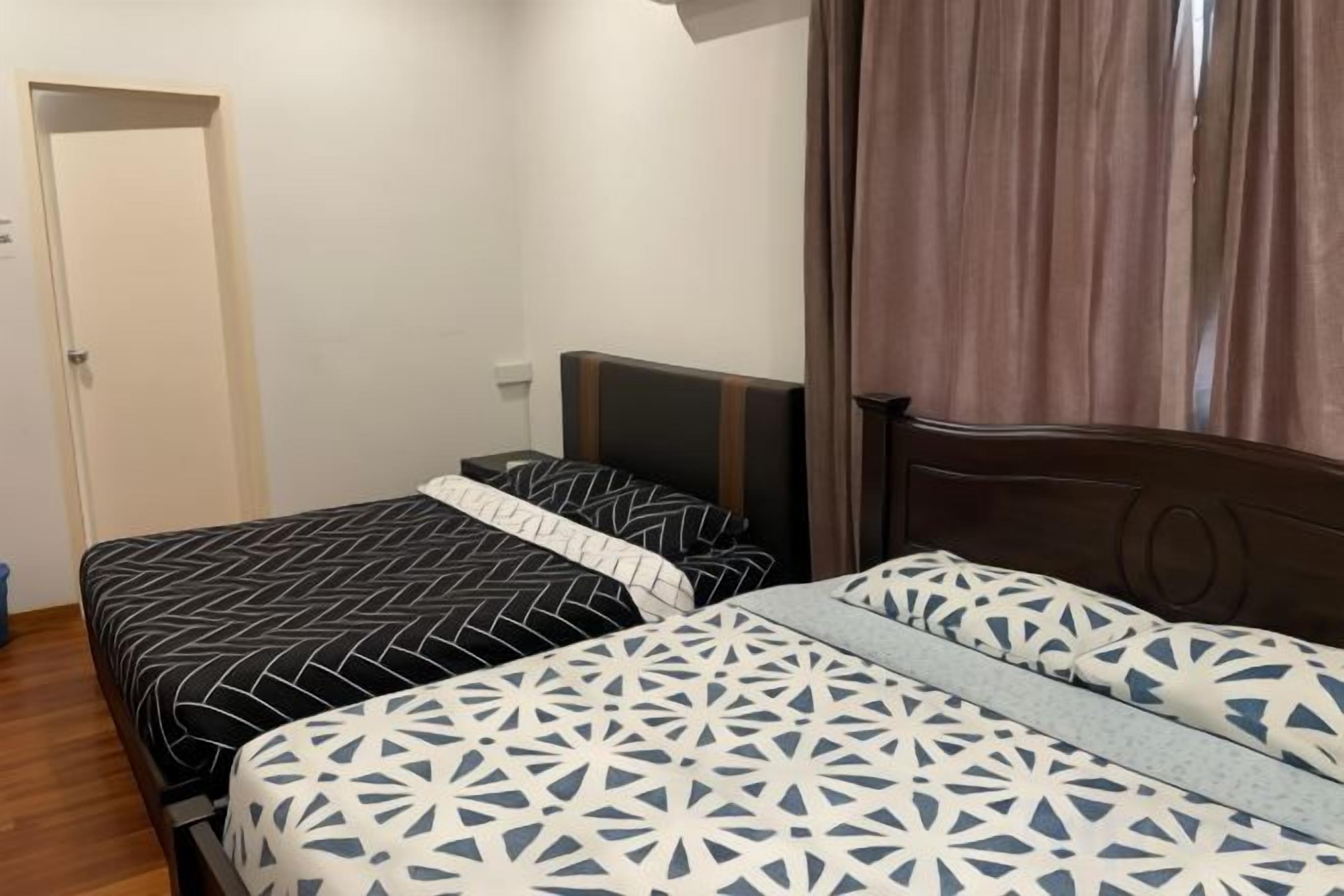 A bedroom with two beds, a wooden headboard, a nightstand, and a door.