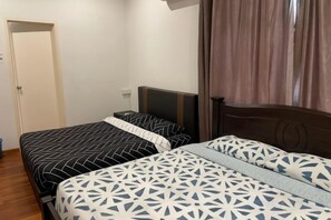 Une chambre avec deux lits, une tête de lit en bois, une table de chevet et une porte.