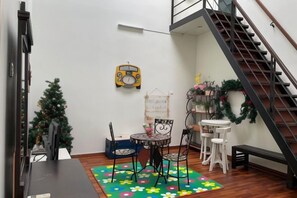 A room with a dining table, chairs, a small Christmas tree, a radio, and a staircase. - Shamrock Beach Villa Penang No19 Sleeps 22 (Tanjung Bungah)