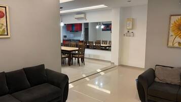 A modern living room with two sofas, a dining area with a table and chairs, and a kitchen in the background.