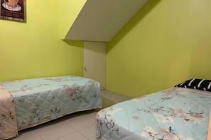 A room with two beds, a sloped ceiling, and a green wall. - Shamrock Beach Villa Penang No19 Sleeps 22 (Tanjung Bungah)
