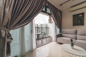 A modern living room with a sofa, a small table with a plant, and a balcony with a table and chairs. - Perling 8scape 3BR Comfy Zone nr Bukitindah/Sutera (Johor Bahru)