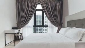 A modern hotel room with a large bed, a desk, and a chair, featuring a view of the city through large windows. - Perling 8scape 3BR Comfy Zone nr Bukitindah/Sutera (Johor Bahru)