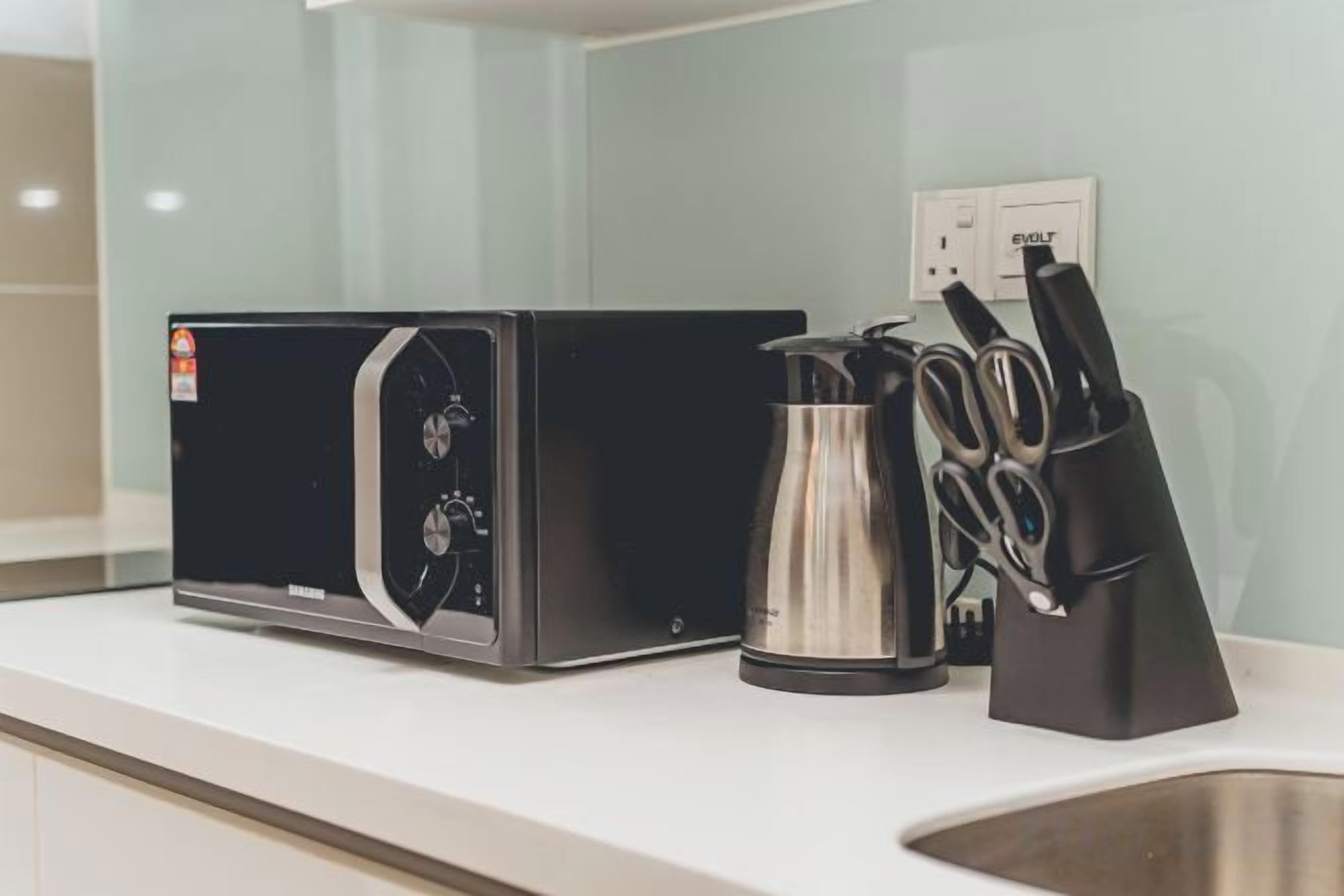 A kitchen counter with a coffee maker, a kettle, and a knife block.