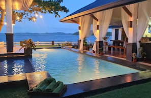 A pool area with a view of the sea, a covered seating area with plants, and a table with towels. - OYO 1175 Casa Ana (Manila)