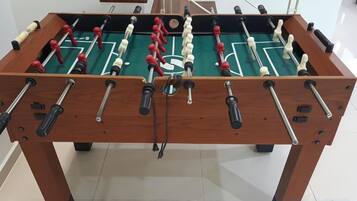 A wooden foosball table with a green playing surface and red and white player figures.