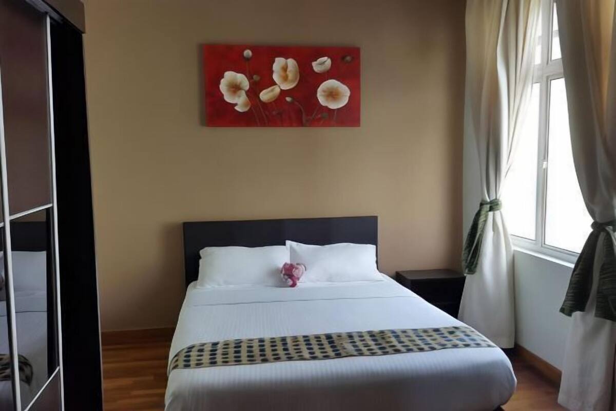 Una habitación de hotel con una cama, un cuadro en la pared y un ventanal con cortinas.