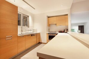 A modern kitchen with wooden cabinets, a white countertop, and a built-in oven. - NOA - Süngü 1 (Istanbul)