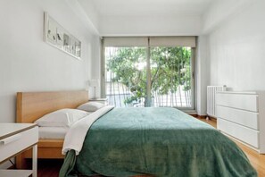 A bedroom with a bed, a nightstand, a dresser, and a window with a view of greenery outside. - NOA - Süngü 1 (Istanbul)
