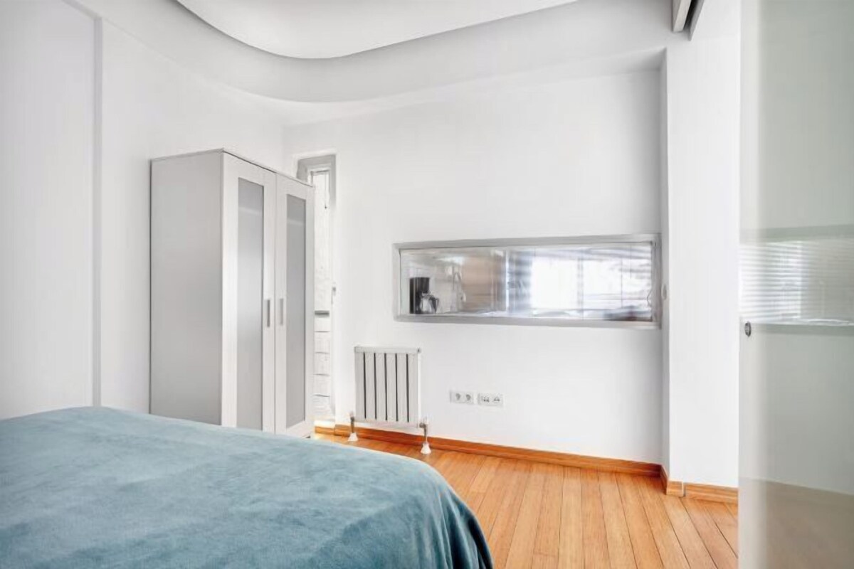 A bedroom with a bed, a wardrobe, a radiator, and a window.
