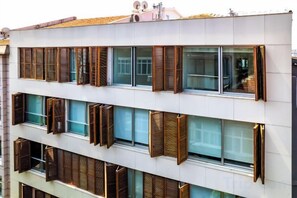 A multi-story building with large windows and shutters.